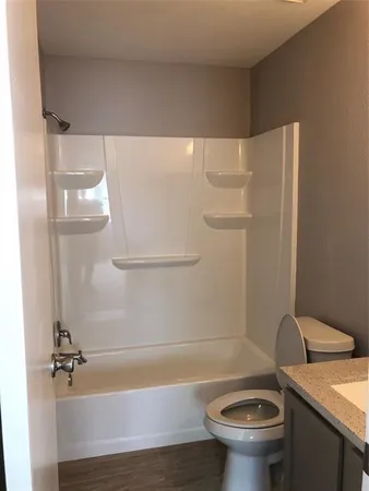 a bathroom with a granite countertop bathtub sink vanity mirror and toilet