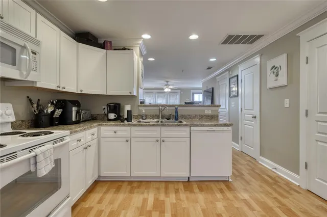 a kitchen with stainless steel appliances granite countertop a stove a sink and white cabinets