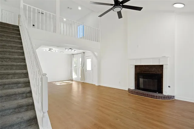 a view of an empty room with wooden floor and a fireplace