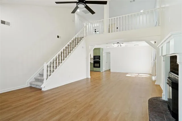 a view of a livingroom with wooden floor a ceiling fan and staircase