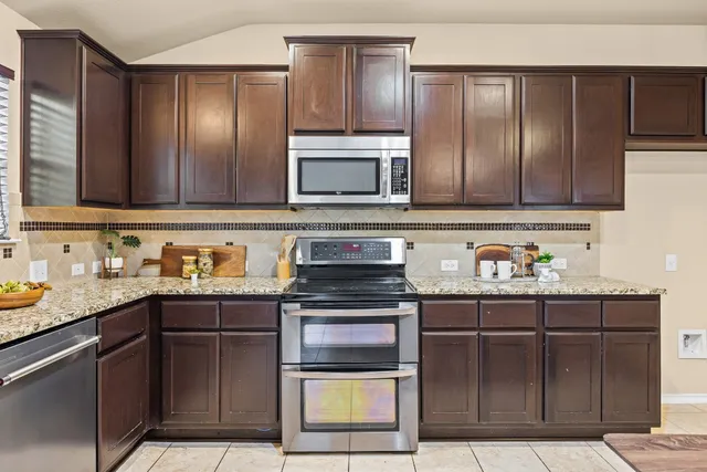 a kitchen with granite countertop stainless steel appliances wooden cabinets a stove top oven
