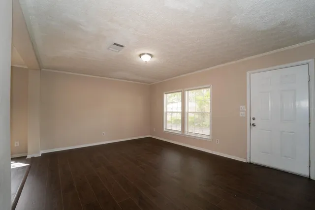 an empty room with wooden floor and windows