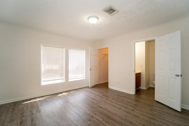 an empty room with wooden floor and windows