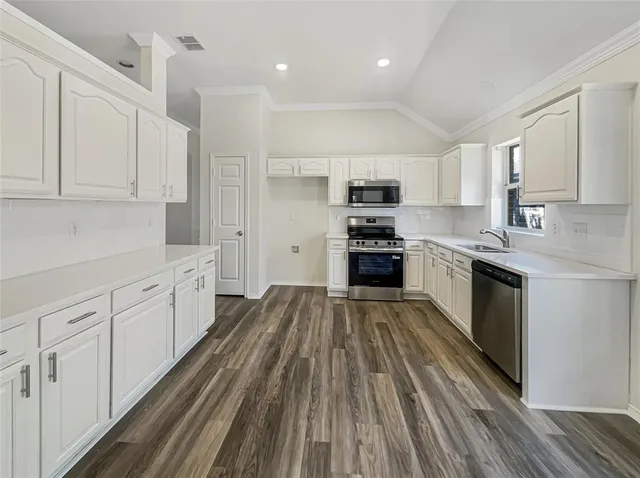 a large kitchen with cabinets stainless steel appliances and window