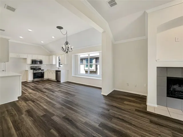 a view of kitchen and empty room with wooden floor