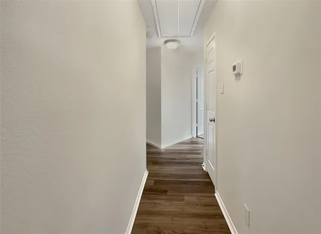 a view of a hallway with a white door and wooden floor