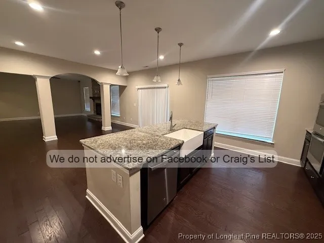 a view of a kitchen with stainless steel appliances granite countertop a sink and a wooden floor