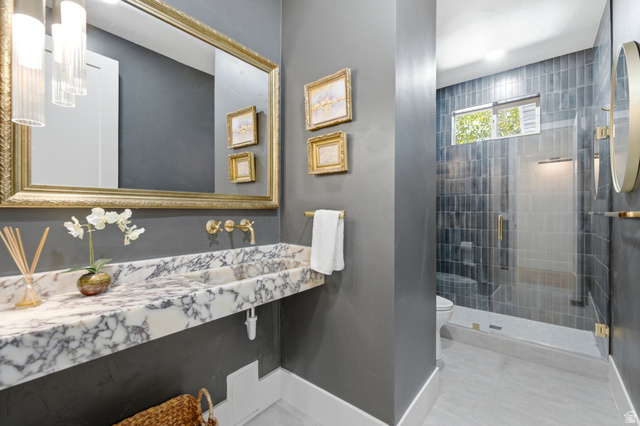3027 Homestead Road Park City, UT 84098 - Photo 15 of 62 Bathroom featuring a floating marble vanity with integrated sink, brass fixtures, a large framed mirror, and a glass-enclosed shower with tiled walls
