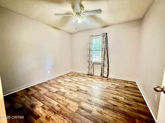 a view of a big room with windows and chandelier fan