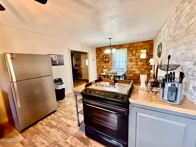 a kitchen with a stove a refrigerator and a view of living room