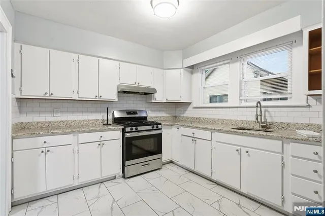 a kitchen with granite countertop white cabinets sink and stainless steel appliances