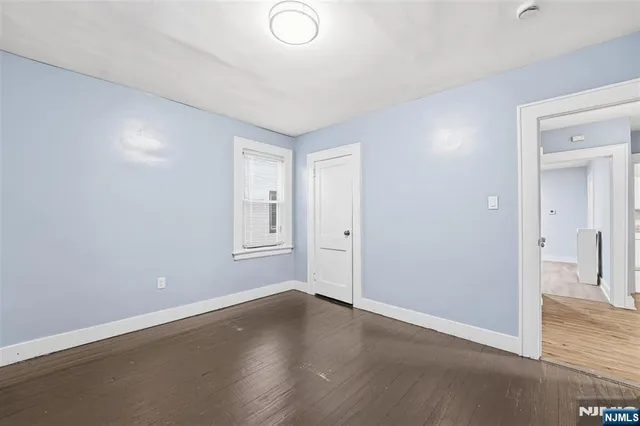 a view of an empty room with wooden floor and a bathroom