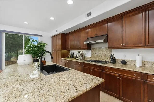 a kitchen with stainless steel appliances granite countertop sink stove refrigerator and cabinets