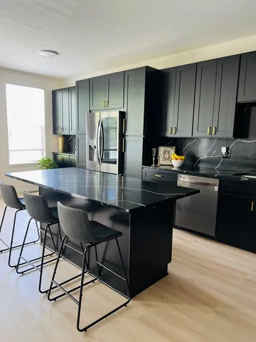 a kitchen with kitchen island granite countertop wooden cabinets and refrigerator