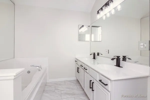 a bathroom with a double vanity sink mirror and bathtub