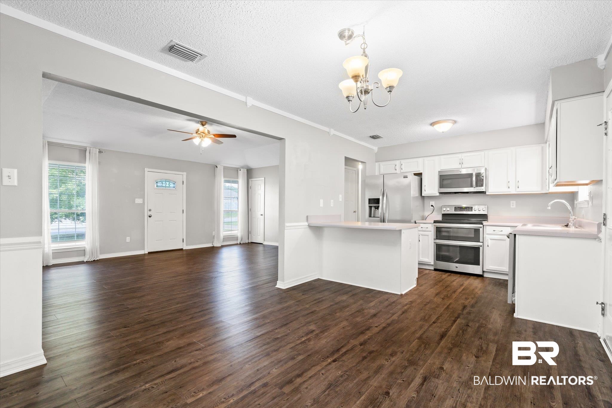 16216 Pointer Drive Foley, AL 36535 - Photo 8 of 21 Open-concept kitchen and living area featuring dark wood-finish flooring, white cabinetry, stainless steel appliances, and a breakfast bar