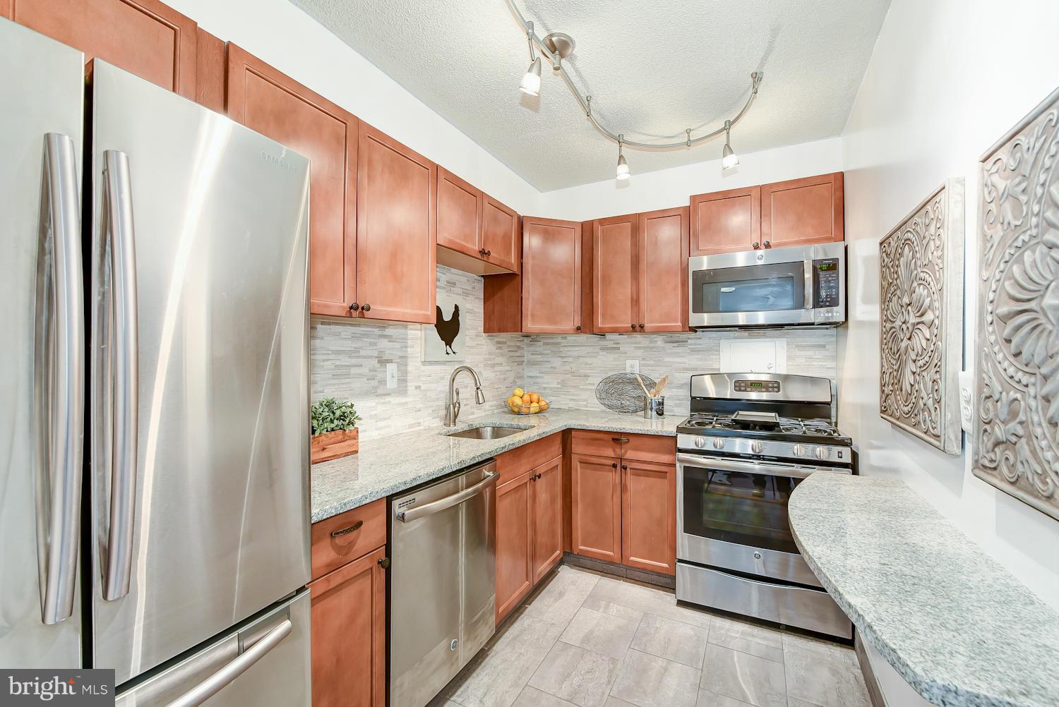 1250 4th Street Southwest, Unit W107 Washington, DC 20024 - Photo 15 of 30 a kitchen with stainless steel appliances granite countertop a refrigerator a sink dishwasher a stove with wooden cabinets