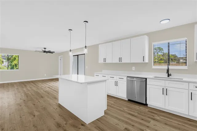 a kitchen with stainless steel appliances granite countertop a sink a stove a refrigerator and white cabinets with wooden floor