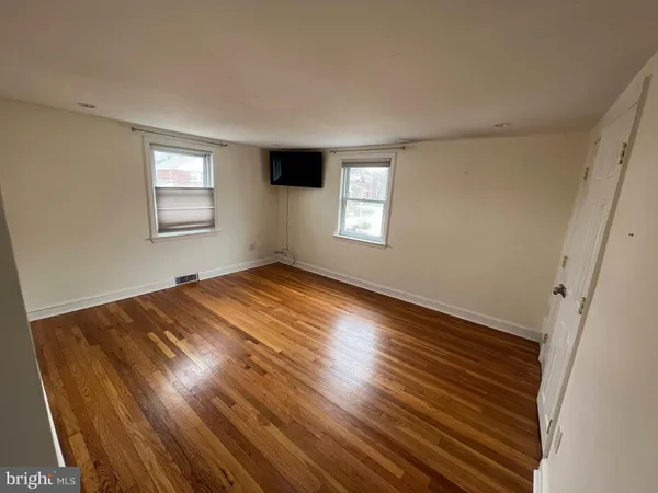 a view of empty room with window and wooden floor