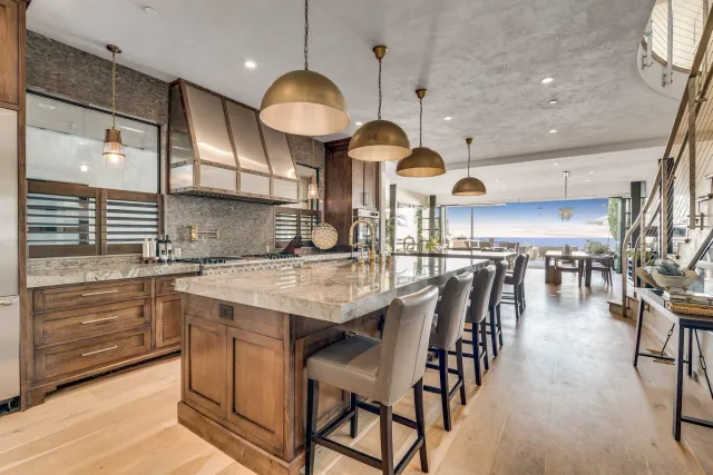 a kitchen with stainless steel appliances kitchen island granite countertop a table chairs sink and cabinets