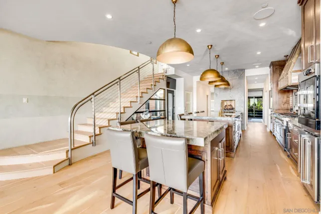 a kitchen with stainless steel appliances kitchen island granite countertop a table chairs and a chandelier