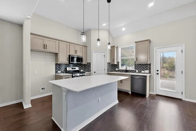 a open kitchen with granite countertop a stove a sink a refrigerator and white cabinets with wooden floor