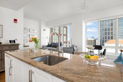 a kitchen with a sink granite counter top a dining table chairs and chandelier