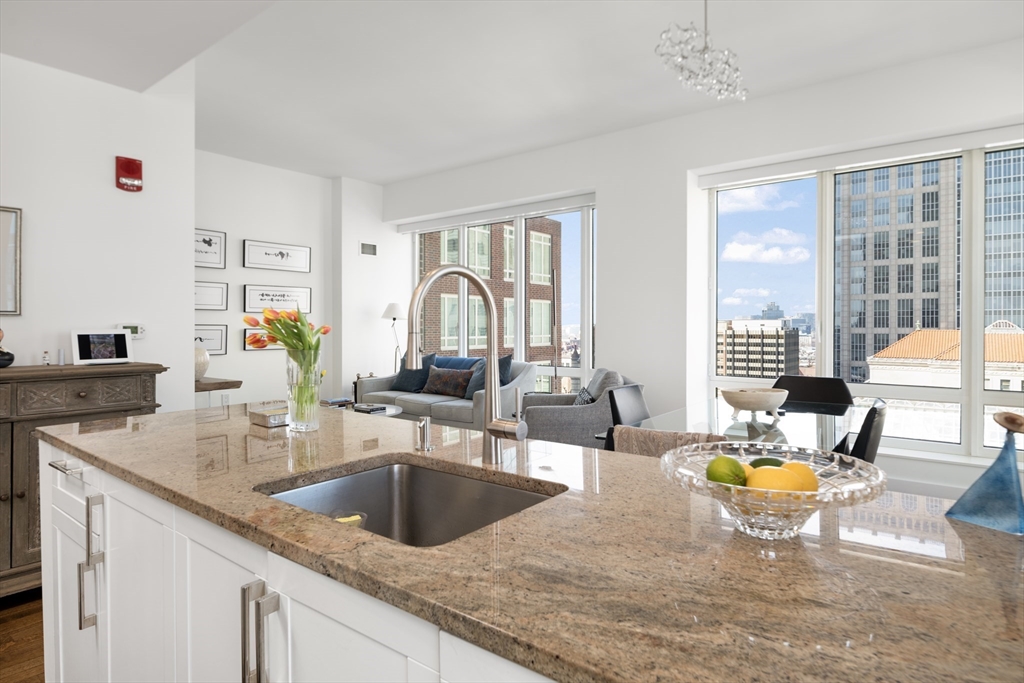 400 Stuart Street, Unit 17B Boston, MA 02116 - Photo 2 of 12 a kitchen with a sink granite counter top a dining table chairs and chandelier