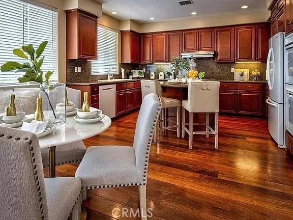 a kitchen with stainless steel appliances kitchen island granite countertop a table chairs and a refrigerator