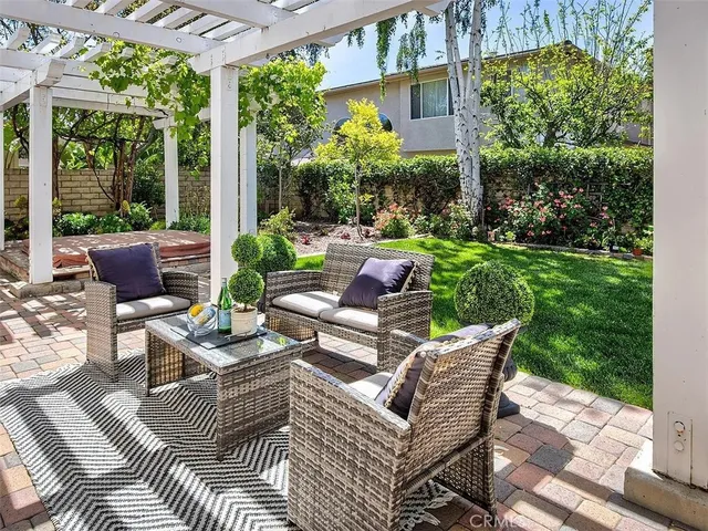 a view of a patio with couches chairs dining table and chairs barbeque grill with a small yard and large trees
