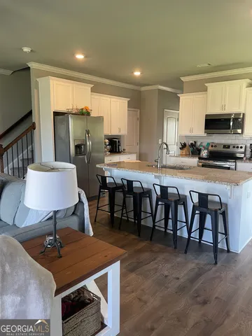 a kitchen with stainless steel appliances kitchen island granite countertop a table chairs sink and cabinets