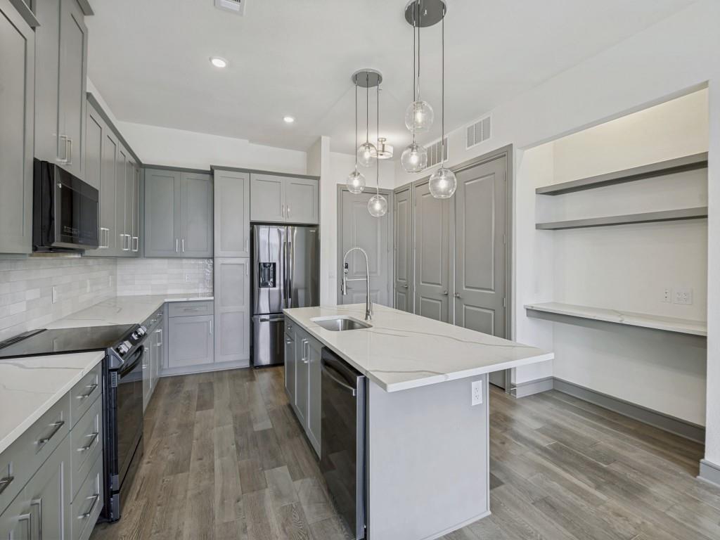 2700 Old Denton Road, Unit 4427 Carrollton, TX 75007 - Photo 3 of 25 a large kitchen with kitchen island a stove a sink a refrigerator and a wooden floor