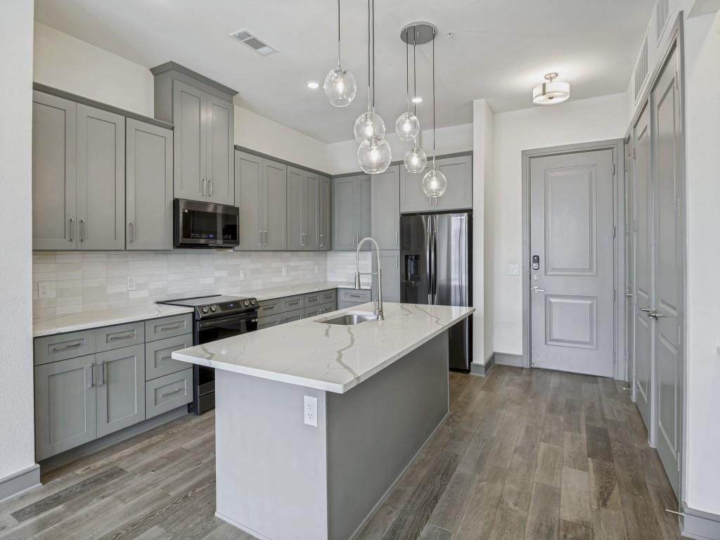 2700 Old Denton Road, Unit 4427 Carrollton, TX 75007 - Photo 4 of 25 a white kitchen with wooden floor and stainless steel appliances