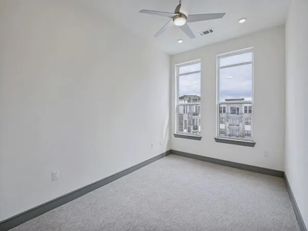 an empty room with windows and fan