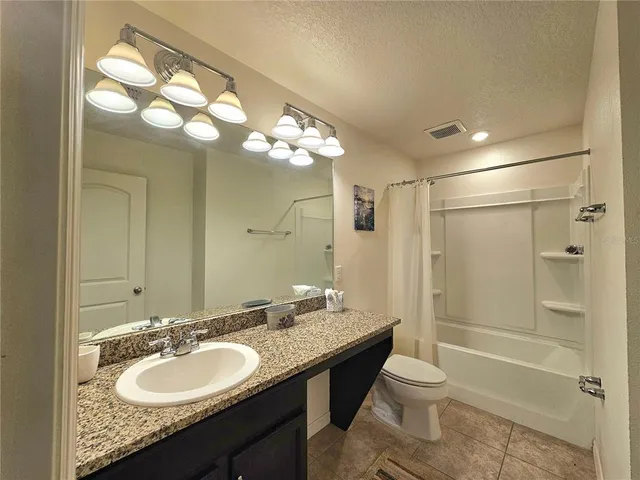a bathroom with a granite countertop sink toilet mirror and shower