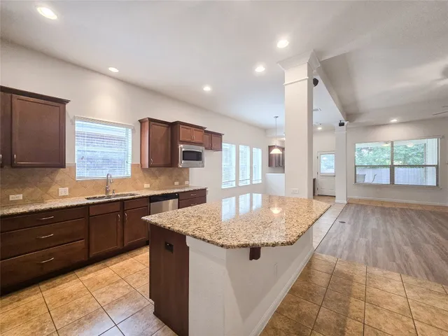 a large kitchen with stainless steel appliances granite countertop a sink dishwasher and a granite countertops with wooden floor