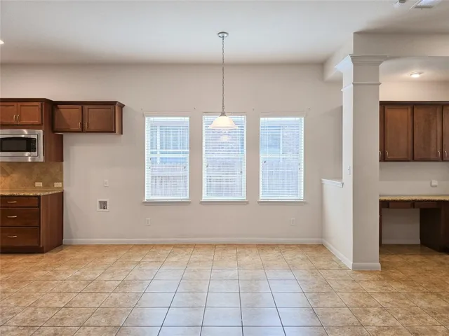 a view of an empty room with a kitchen and a window