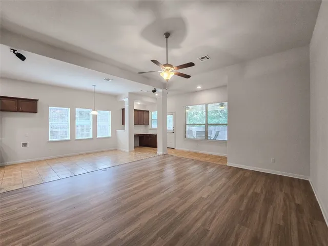 a view of empty room with wooden floor and fan