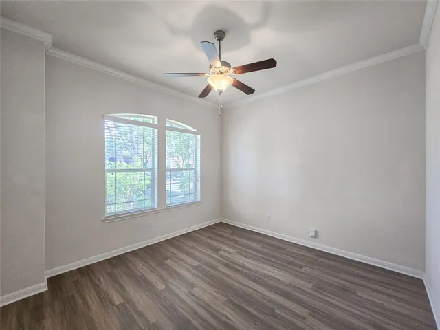 an empty room with wooden floor fan and windows