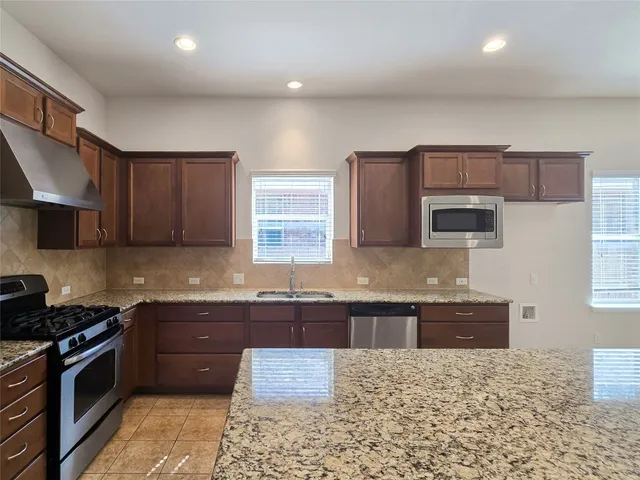 a large kitchen with granite countertop a stove top oven a sink a counter space and cabinets