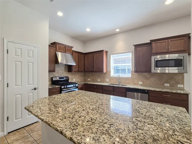 a kitchen with stainless steel appliances granite countertop a stove a sink and a microwave
