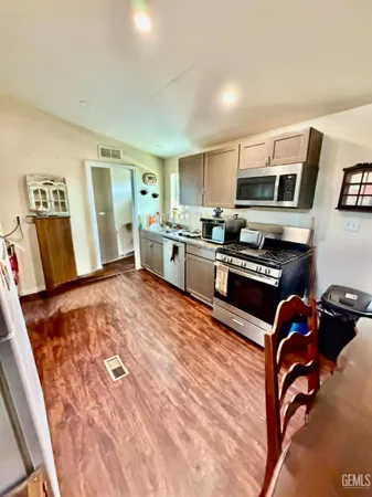 a kitchen with stainless steel appliances granite countertop a stove top oven a sink a dining table and chairs with wooden floor