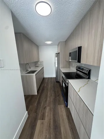 a kitchen with a sink a stove top oven and wooden floor
