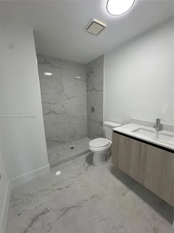 a bathroom with a granite countertop sink a toilet and shower