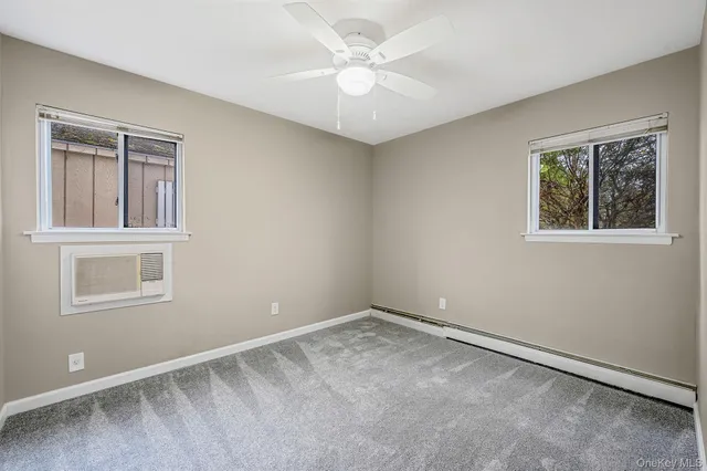 an empty room with a chandelier fan and closet area