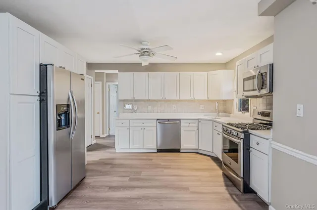 a kitchen with cabinets stainless steel appliances and a window