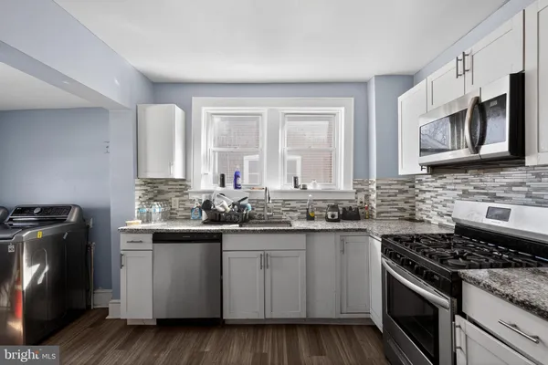 a kitchen with stainless steel appliances granite countertop a stove a sink and a microwave
