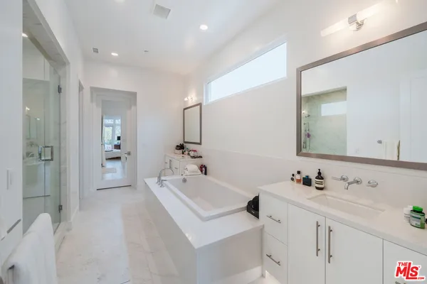 a bathroom with a bathtub sink vanity and mirror