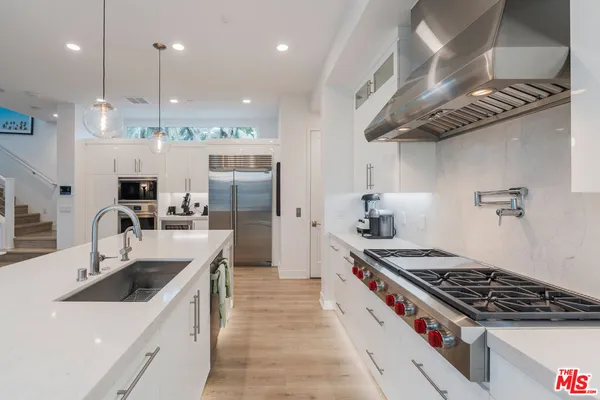 a kitchen with stainless steel appliances granite countertop a sink a stove and a refrigerator