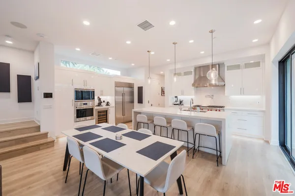 a kitchen with stainless steel appliances kitchen island granite countertop a kitchen island a stove a table and a refrigerator